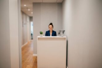 Bureau d'accueil compact dans un couloir étroit de petit bureau moderne avec une hôtesse souriante en blazer marine
