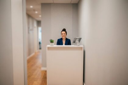 Bureau d'accueil compact dans un couloir étroit de petit bureau moderne avec une hôtesse souriante en blazer marine